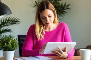 Woman entrepreneur working through GEO audit checklist at desk, reviewing online business optimisation tasks
