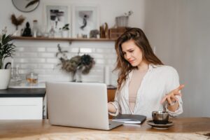 Confused woman sitting at laptop looking puzzled while working