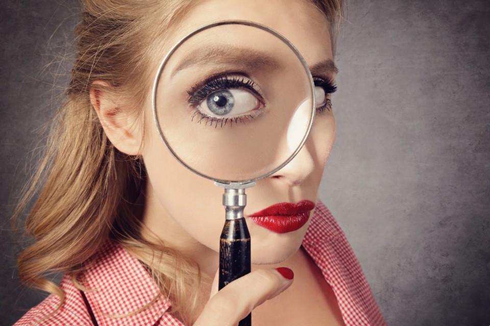 Woman entrepreneur holding magnifying glass examining AI content patterns and structure for GEO optimisation
