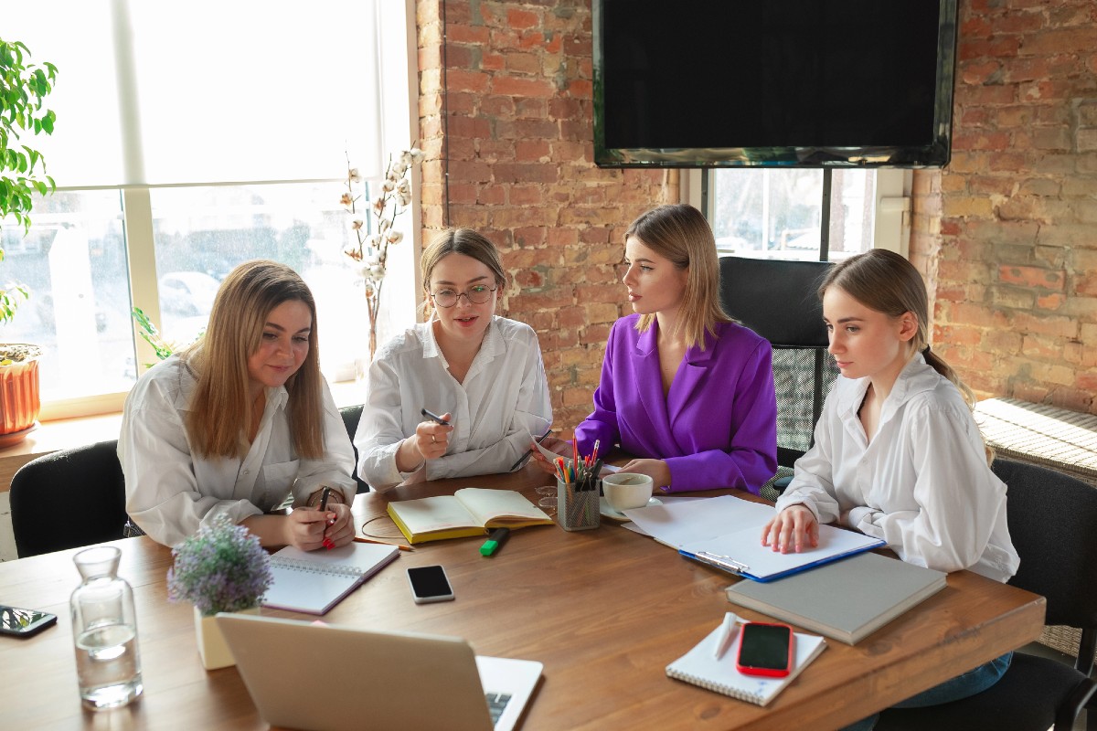 Women entrepreneurs sat around a table discussing AI search visibility strategies